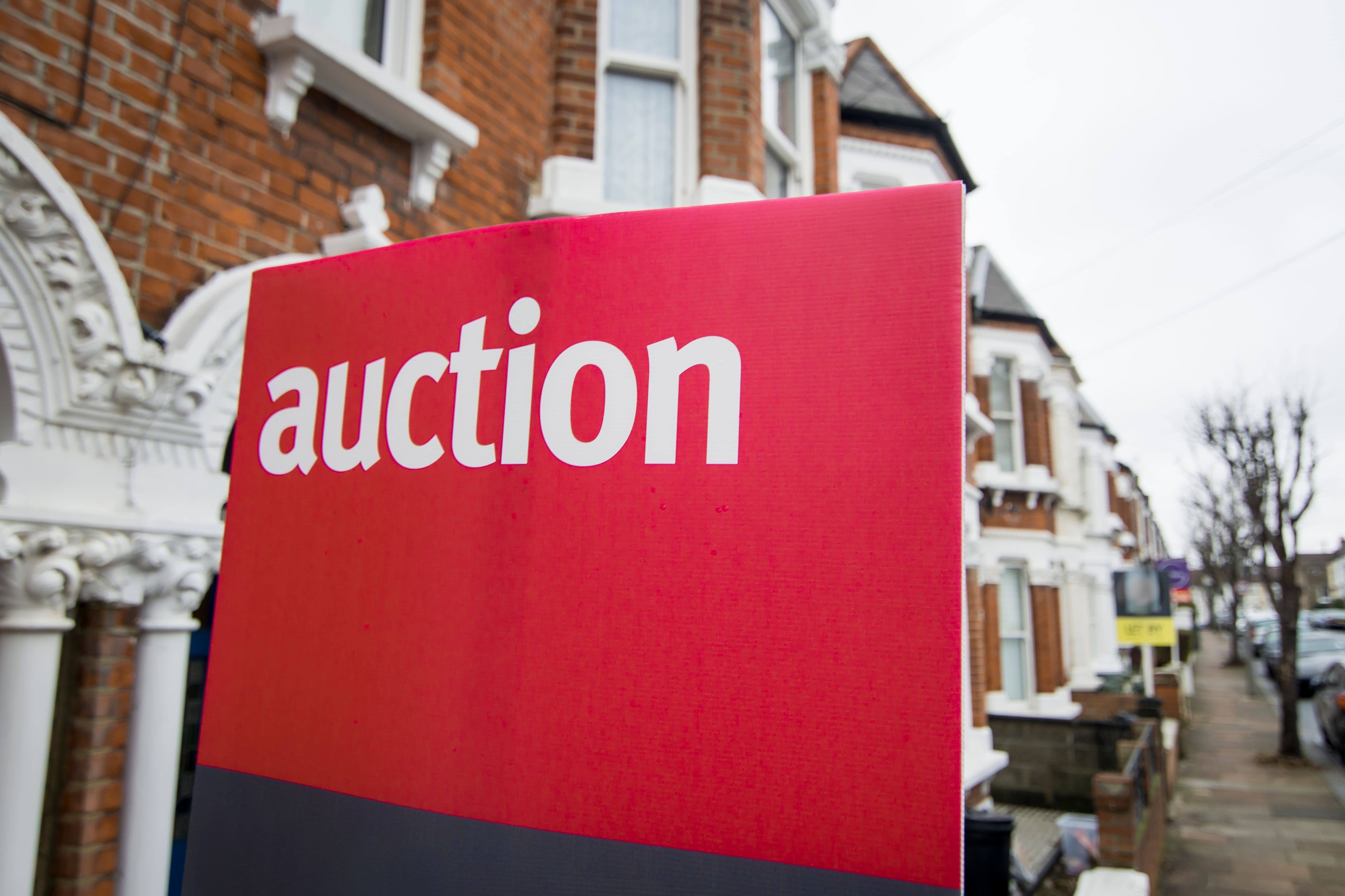 Red auction sign outside a row of terraced houses in the UK